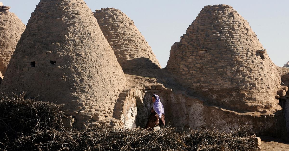 Photo of woman standing in front of cone-shaped houses made of mud in Turkey's Harran province in 2008. 