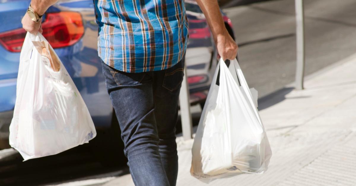 Man carrying two grocery bags of plastic.