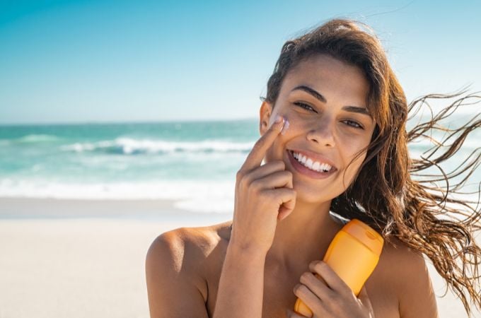 non toxic sunscreen for face - woman at beach applying sunscreen